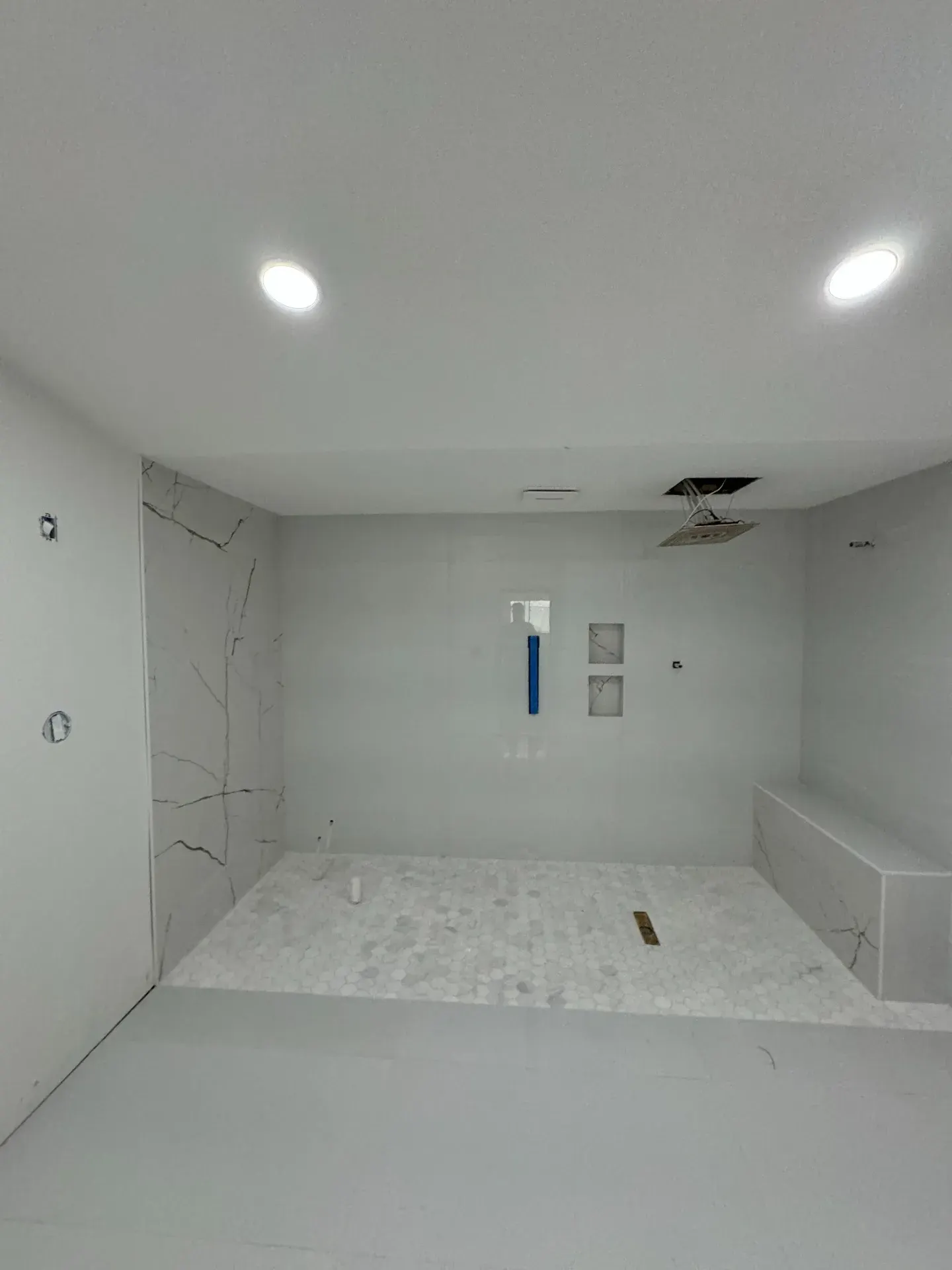 Large white shower with marble-look tile